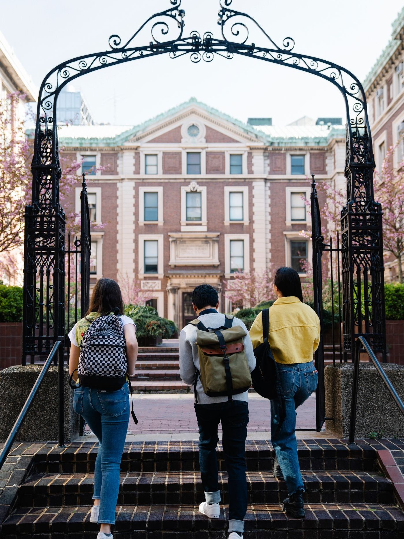 Three students with backpacks walking through a campus gate